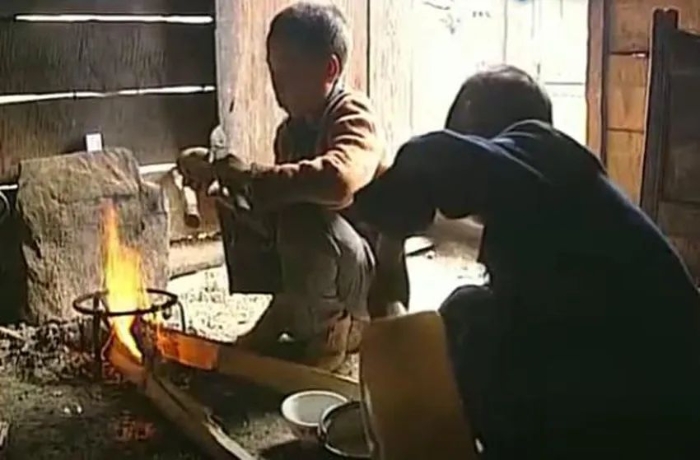 2幼时的杨灿彪（右）和哥哥在小木屋里生火做饭。来源：纪录片《学生村》视频截图