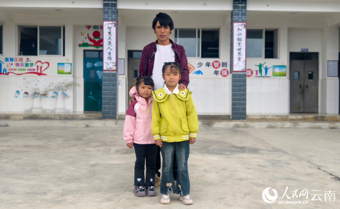 6杨灿彪和两个女儿在天灯完小教学楼前合影。人民网记者 符皓摄